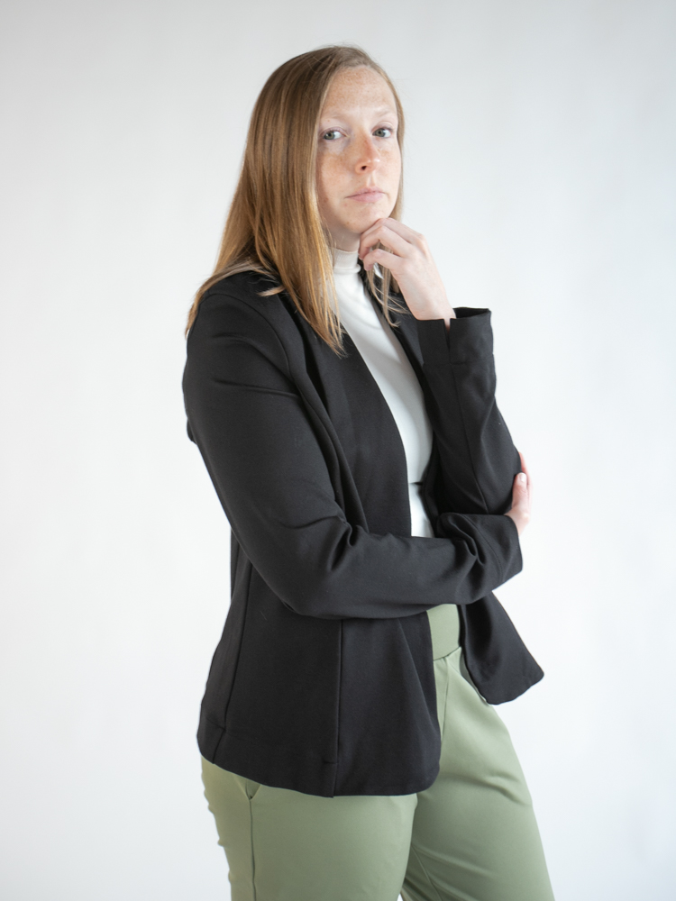 Leslye Young in a black blazer, white turtleneck, and olive trousers — a Workery Apparel look.