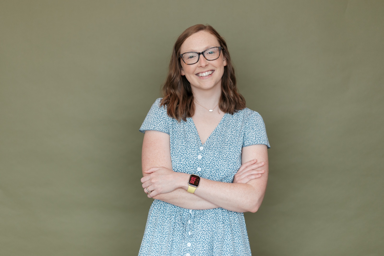 Leslye Young, fashion designer and consultant, smiling against an olive green backdrop.