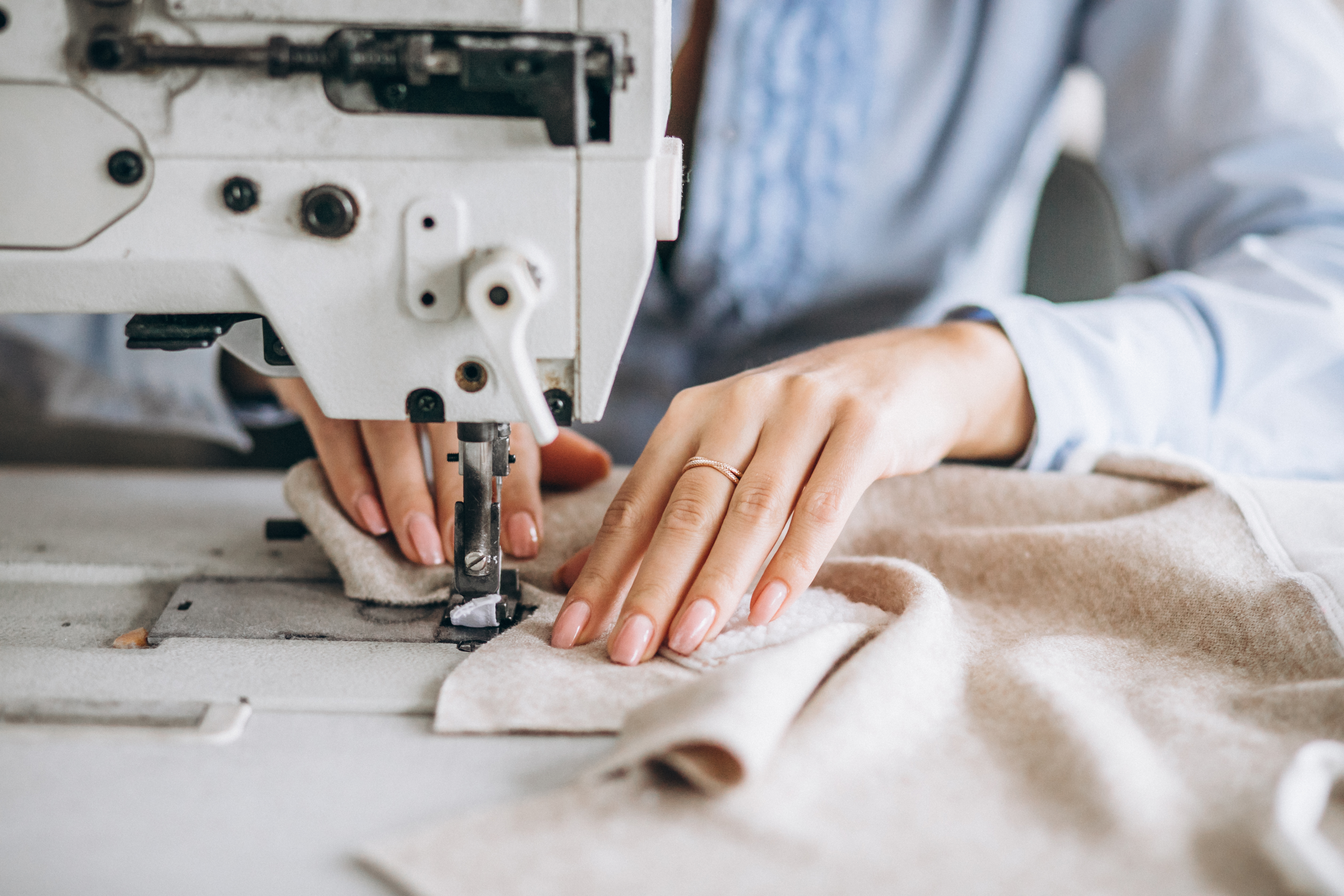 A sample maker guiding fabric through an industrial sewing machine, building a first sample.